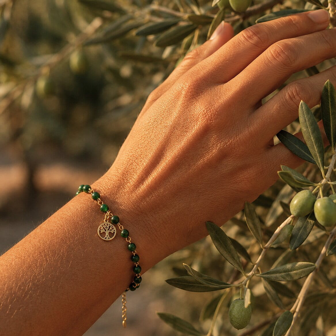 Hand wearing the Voubes Bracelet, touching an olive tree branch.