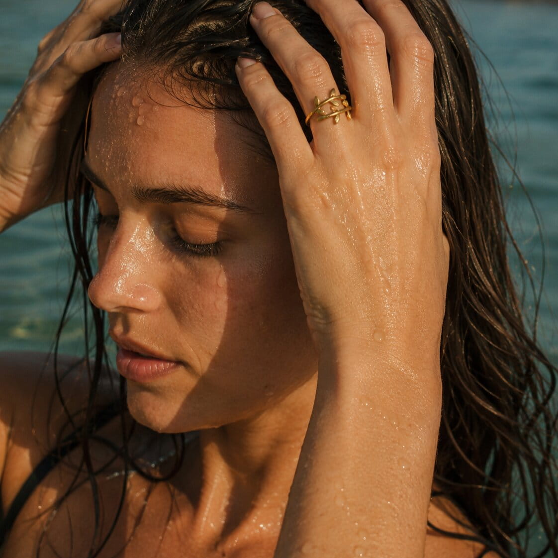 [variant:Vouves Ring] Woman with wet hair by the water, wearing a the Vouves ring